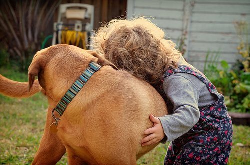 child hugging her dog